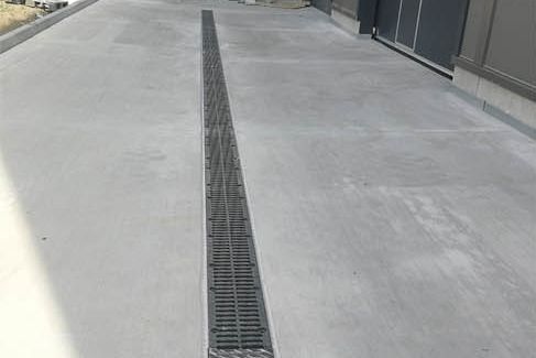 Verfugte Entwässerungsrinne in der Betonfläche vor einer Industriehalle