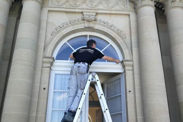 Verfugung am Rundbogenfenster eines historischen Sandsteinportals, Mitarbeiter auf der Leiter