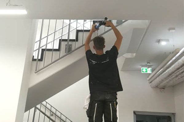 Mitarbeiter verfugt über Kopf die Anschlussfuge an der Decke eines neuen Treppenhauses