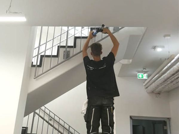 Anschlussfuge an der Decke eines Treppenhaus-Neubaus wird verfugt